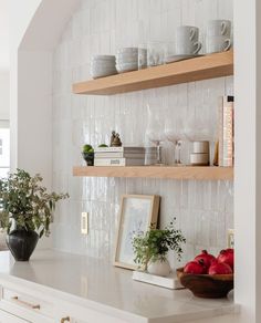 the shelves in this kitchen are filled with plates and bowls, cups, and vases