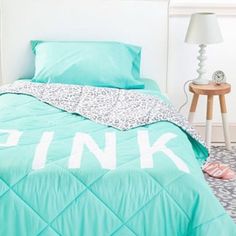 a bed with pink letters on the comforter and matching sheets in a bedroom setting