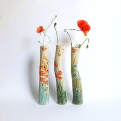 three vases with flowers painted on them are lined up next to each other in front of a white background