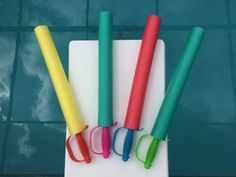 four different colored toothbrushes sitting on top of a cutting board next to a pool