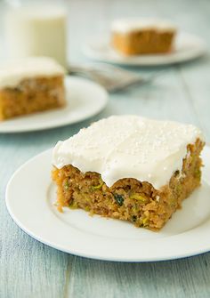 a piece of carrot cake with white frosting on a plate next to a glass of milk