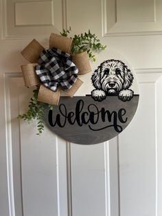 a welcome sign with a dog on it hanging from the side of a white door