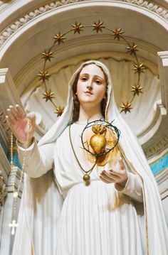 a statue of the immaculate mary holding a heart