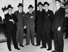 a group of men in suits and hats standing next to each other