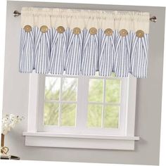 a blue and white striped window curtain with buttons on the valance, hanging in front of