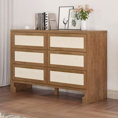 a wooden dresser with drawers and pictures on it's top, against a white wall