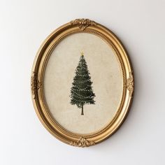 a painting of a pine tree in a gold frame on a white wall behind it