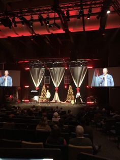 two men on stage with christmas trees in front of them