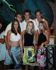 a group of young people standing next to each other in front of a large statue