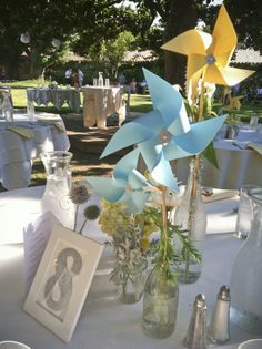 a table topped with vases filled with flowers next to pictures and photos on tables