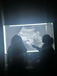 two people are standing in front of a large screen with an image of the moon on it