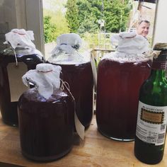 three jars filled with liquid sitting on top of a wooden table next to a bottle