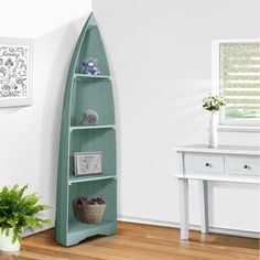 a room with a green shelf next to a white desk and potted plant on the floor