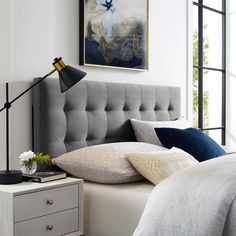 a bedroom with white walls and gray headboard