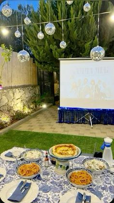 an outdoor movie is set up on the lawn with food and drinks in front of it