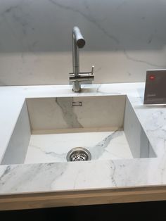 a white sink sitting under a faucet on top of a marble countertop