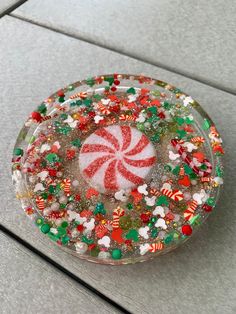 a glass dish with candy and candies in it sitting on the ground next to a tile floor