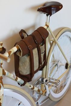 a bicycle with a bag attached to the handlebars next to a white wall