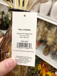 a person is holding up a label for a flower arrangement in a store display case