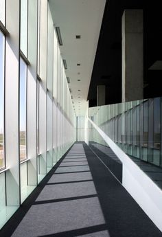 an empty hallway with lots of windows on both sides and carpeted flooring in between