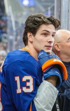 the hockey player is holding his glove in one hand and looking off into the distance