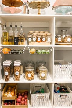 an organized pantry filled with lots of food and condiments, including apples, oranges