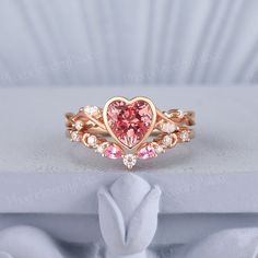 a heart shaped ring with pink and white stones in it on top of a table