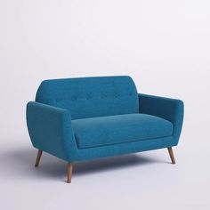 a blue couch sitting on top of a white floor next to a wooden leg chair