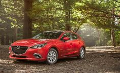 a red mazda car parked in the woods