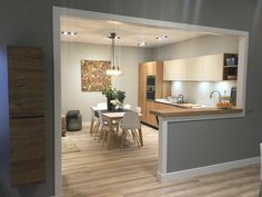 an open concept kitchen and dining room with wood flooring, white walls and cabinets