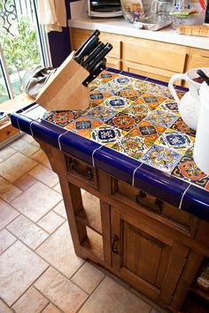 a kitchen island covered in colorful tiles and utensils on top of it next to a window