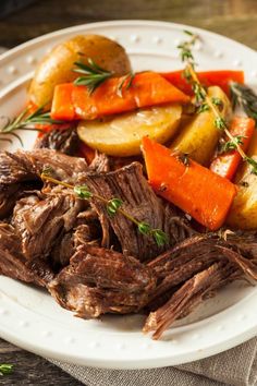 a white plate topped with roast, carrots and potatoes on top of a table