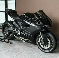 a black motorcycle parked in front of a wall next to a window on a tile floor