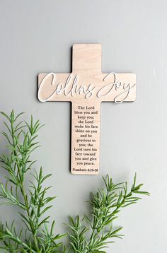 a wooden cross with the words collis boy on it next to some green plants