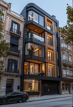 a car is parked in front of a tall building with balconies and windows