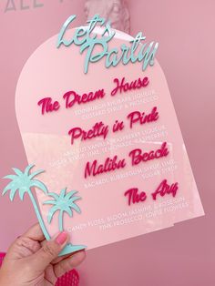 a person holding up a sign that says let's party the dream house pretty in pink malibu beach