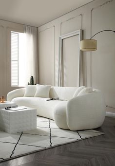 a white couch sitting on top of a wooden floor next to a table and chair