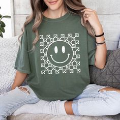 This t-shirt combines the timeless appeal of checkered patterns with the joyful charm of floral and smiley motifs. Sure to bring a smile to your face (and others'), it adds a playful touch to any outfit. Make a statement with this fun and trendy t-shirt! Features: 100% USA Cotton Preshrunk Sizing is unisex & true to size. Size up for an oversized fit. Color: Moss Super cozy & will hold their shape wash after wash.(Machine wash cold & tumble dry) Smiley Face Shirt, Trendy Tshirts, Checkered Pattern, Smiley Face, Cricut Crafts, A Smile, Smiley, Bring It On, Floral