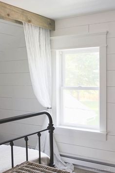 a bed sitting under a window next to a white wall