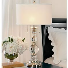 a nightstand with a lamp and flowers on it