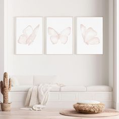 three pink butterfly prints hanging on the wall above a white couch