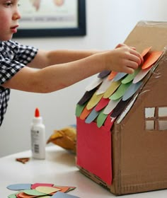 a young boy making a house out of construction paper