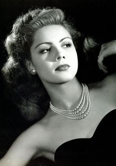 an old black and white photo of a woman wearing pearls