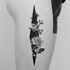 a black and white photo of a woman's thigh with roses on it, in the shape of an arrow