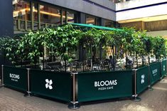 a group of tables that have plants growing out of them in front of a building