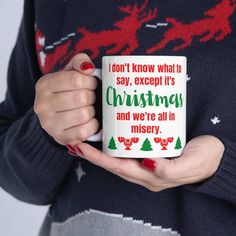 a woman is holding a coffee mug with christmas sayings on it and santa's sleigh in the background