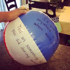 a person holding a beach ball with writing on it in front of a dining room table