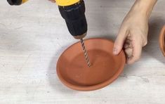 a person using a drill on a clay bowl with a screwdriver in it