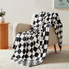 a black and white blanket sitting on top of a chair next to a potted plant