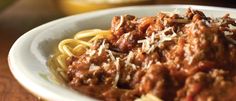 a white bowl filled with spaghetti and meat sauce